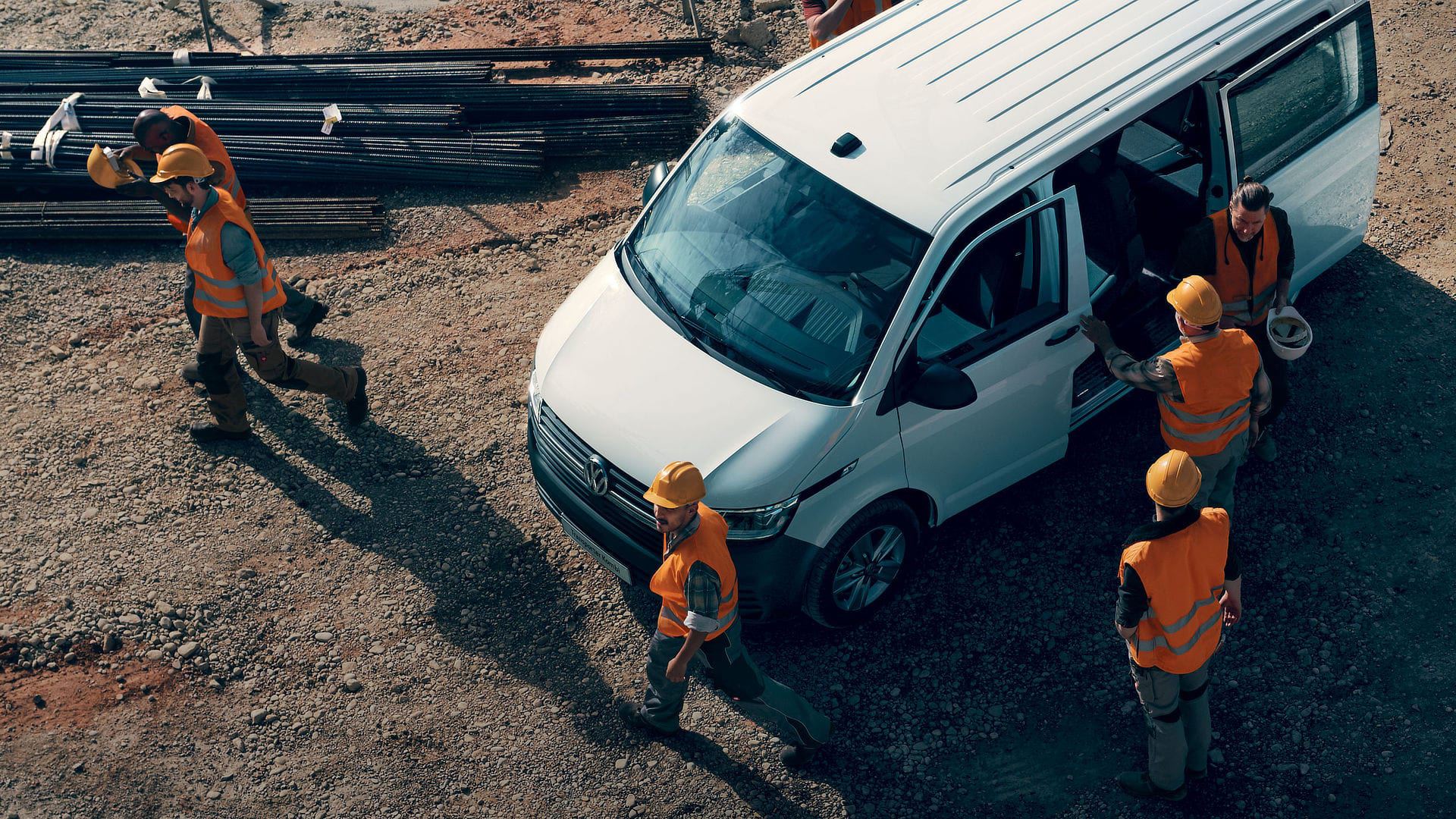 Volkswagen Transporter Kombi ripreso dall'alto in un cantiere, circondato da operai al lavoro.